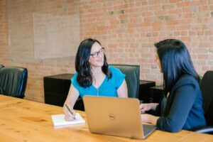 Two colleagues talking through work at a table.